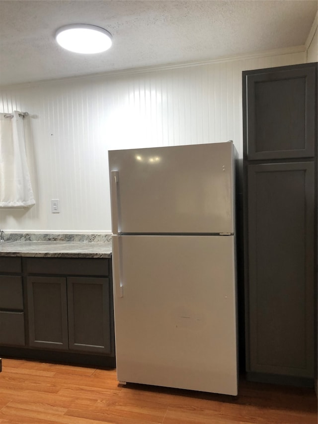 kitchen with stainless steel fridge, a textured ceiling, and light wood-type flooring