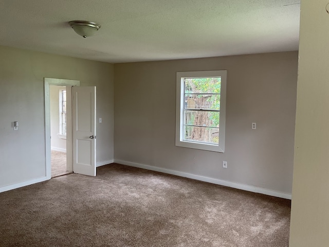 carpeted empty room featuring a textured ceiling