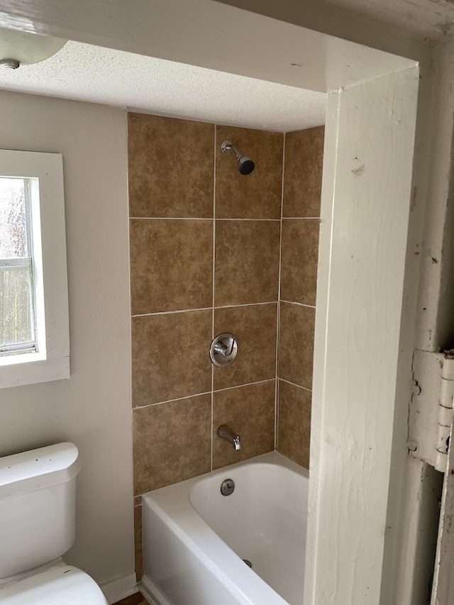 bathroom with toilet and tiled shower / bath