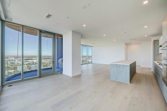 kitchen featuring floor to ceiling windows, a kitchen island, and light wood-type flooring