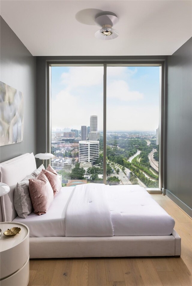 bedroom featuring expansive windows, light wood-type flooring, and multiple windows