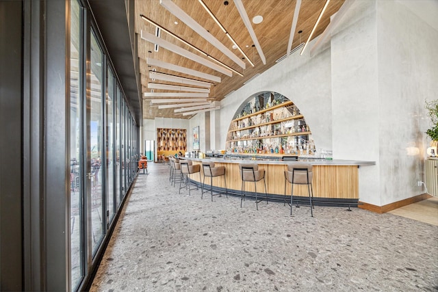 bar featuring wood ceiling and a towering ceiling