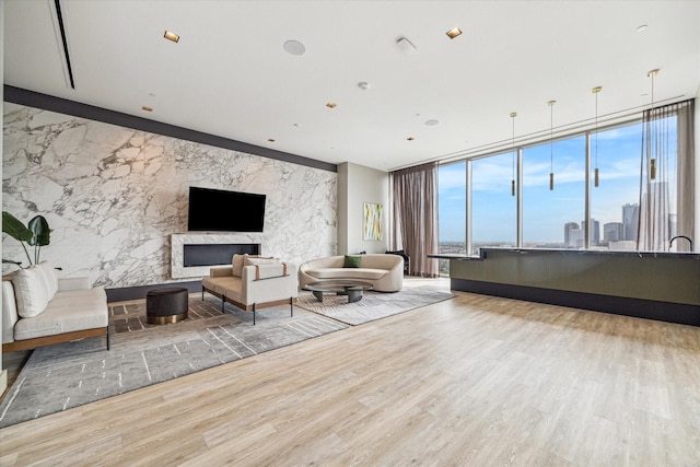 living room featuring a wall of windows, a fireplace, and light hardwood / wood-style flooring