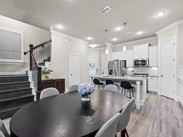 dining area with light hardwood / wood-style floors and ornamental molding