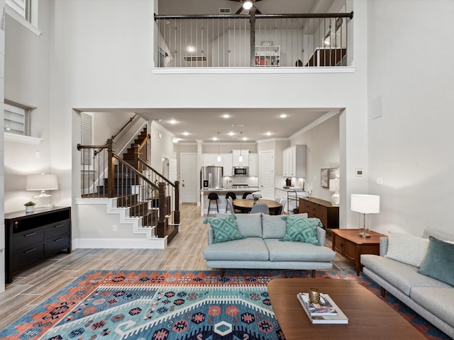 living room featuring a high ceiling, ornamental molding, and light hardwood / wood-style flooring