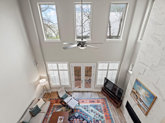 living room featuring french doors, light hardwood / wood-style floors, a high ceiling, and ceiling fan