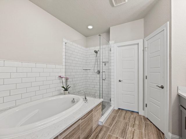 bathroom with vanity, plus walk in shower, and a textured ceiling