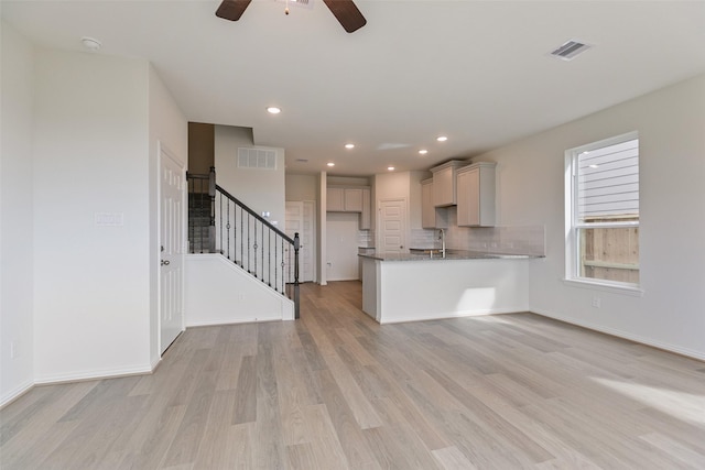 kitchen featuring light wood finished floors, visible vents, backsplash, and a sink