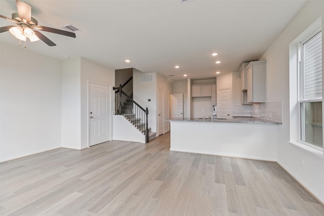 kitchen featuring light wood finished floors, visible vents, a peninsula, and light stone counters