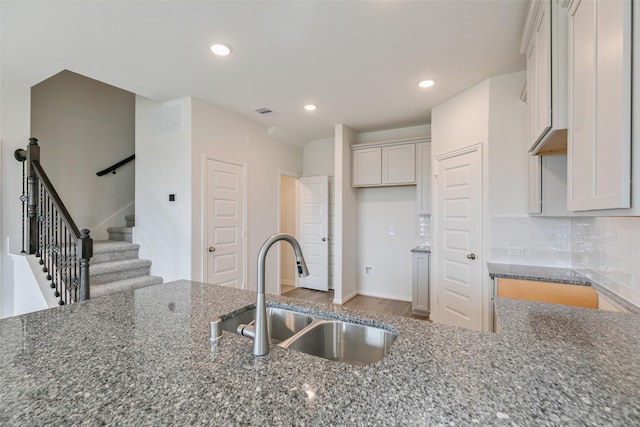 kitchen with visible vents, dark stone counters, recessed lighting, a sink, and decorative backsplash