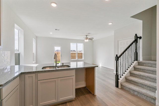 kitchen with visible vents, light stone counters, recessed lighting, wood finished floors, and a sink