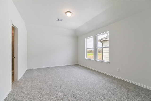 carpeted empty room featuring lofted ceiling, baseboards, and visible vents