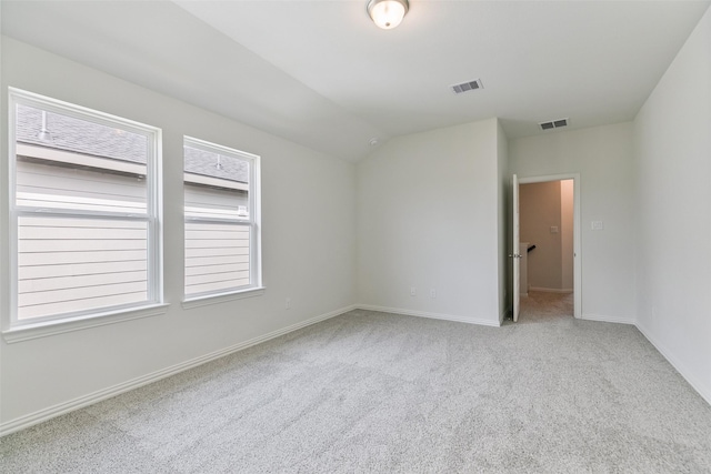 carpeted empty room featuring visible vents, baseboards, and lofted ceiling