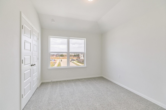 unfurnished room with carpet flooring, baseboards, and lofted ceiling