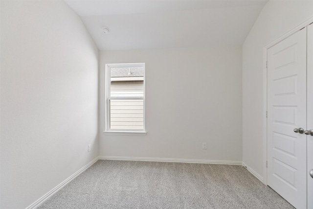 empty room featuring baseboards, light carpet, and lofted ceiling