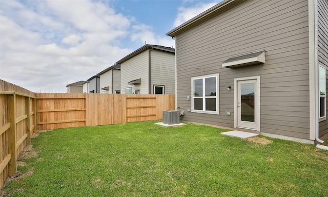 rear view of house with a lawn, cooling unit, and a fenced backyard