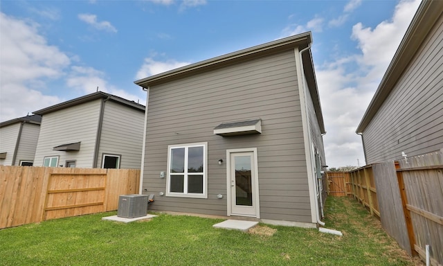 rear view of property featuring cooling unit, a lawn, and a fenced backyard