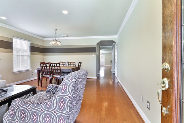 living room with ornamental molding, wood-type flooring, and an inviting chandelier