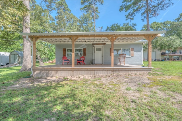 back of property featuring covered porch, a yard, and a shed