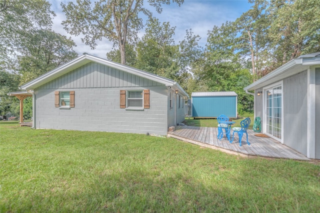 back of house with a wooden deck, a yard, and a storage unit