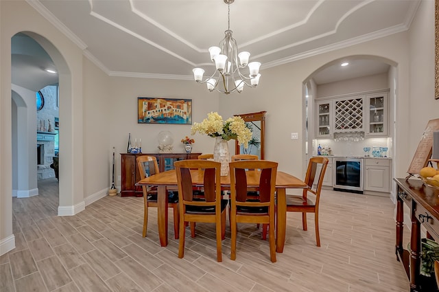 dining space with ornamental molding, wine cooler, and a chandelier