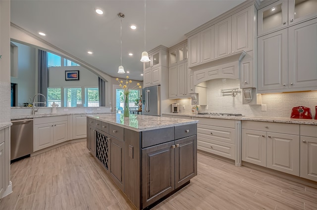 kitchen featuring stainless steel appliances, a kitchen island, sink, and light wood-type flooring