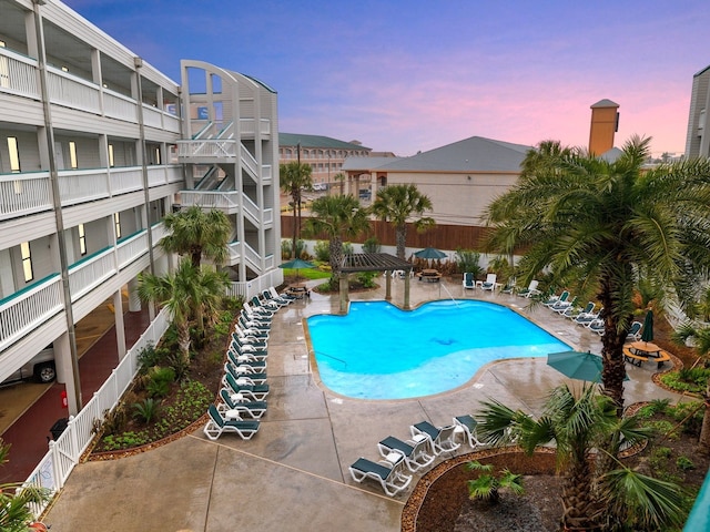 pool at dusk featuring a patio