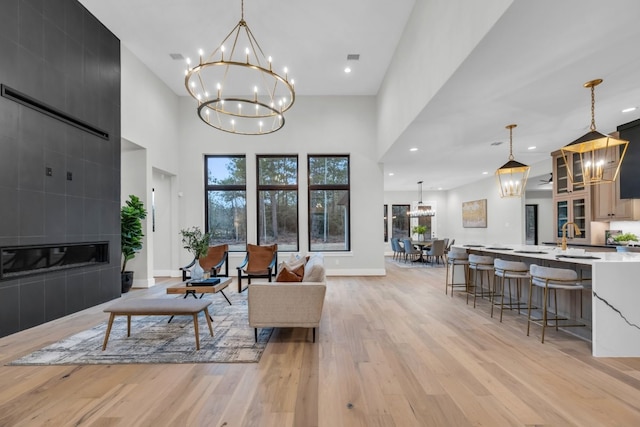 living room with a fireplace, sink, a notable chandelier, and light hardwood / wood-style floors