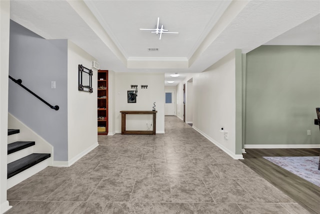 corridor with crown molding, a raised ceiling, a textured ceiling, and light hardwood / wood-style flooring