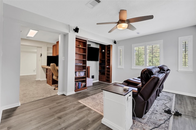 living room with a textured ceiling, wood-type flooring, and ceiling fan