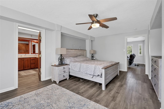 bedroom with a textured ceiling, dark hardwood / wood-style floors, connected bathroom, sink, and ceiling fan