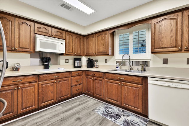 kitchen with light hardwood / wood-style flooring, white appliances, and sink