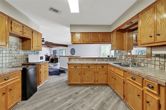 kitchen with light hardwood / wood-style flooring, backsplash, tile counters, and sink