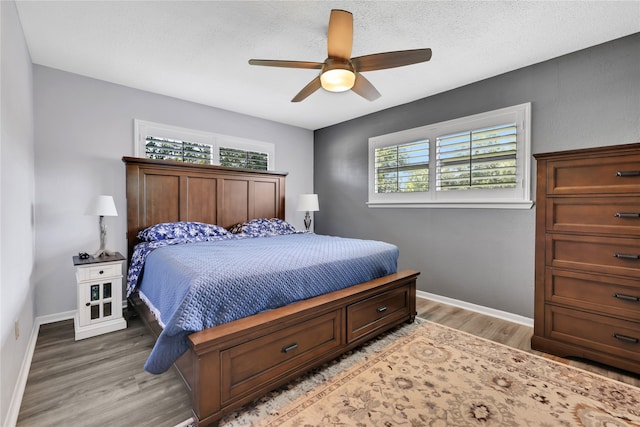 bedroom with multiple windows, a textured ceiling, hardwood / wood-style floors, and ceiling fan