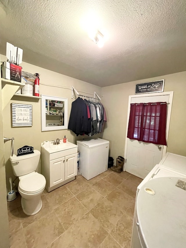 washroom featuring washing machine and clothes dryer, sink, and a textured ceiling