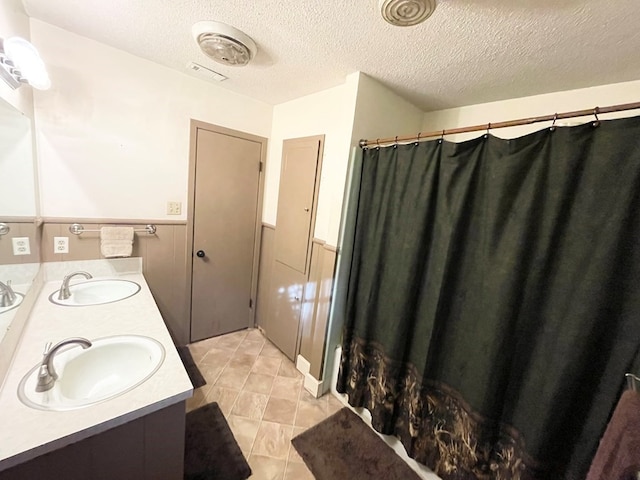 bathroom with vanity, a textured ceiling, and tile patterned flooring