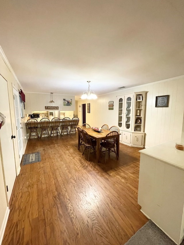 dining room with a chandelier, dark hardwood / wood-style flooring, and crown molding