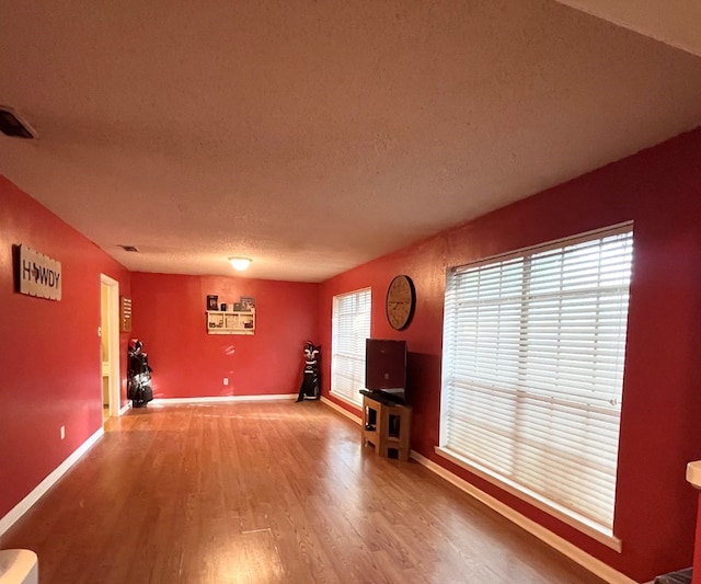 unfurnished living room with wood-type flooring and a textured ceiling