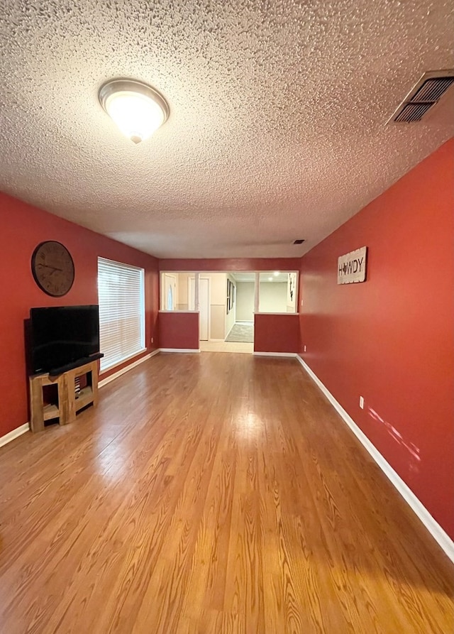 unfurnished living room with wood-type flooring and a textured ceiling