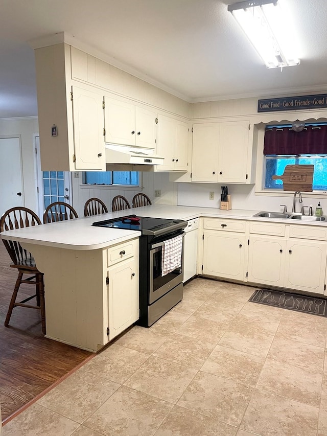 kitchen featuring a breakfast bar area, stainless steel electric range, crown molding, sink, and light wood-type flooring