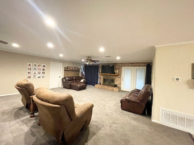 carpeted living room with ceiling fan, a fireplace, and crown molding