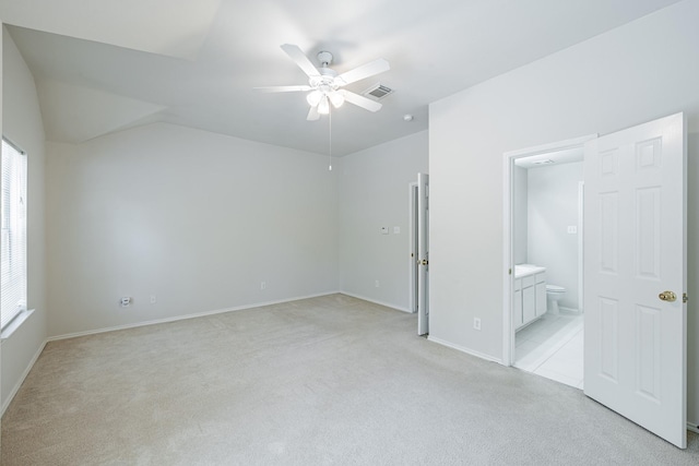 unfurnished bedroom featuring vaulted ceiling, light colored carpet, ceiling fan, and ensuite bath