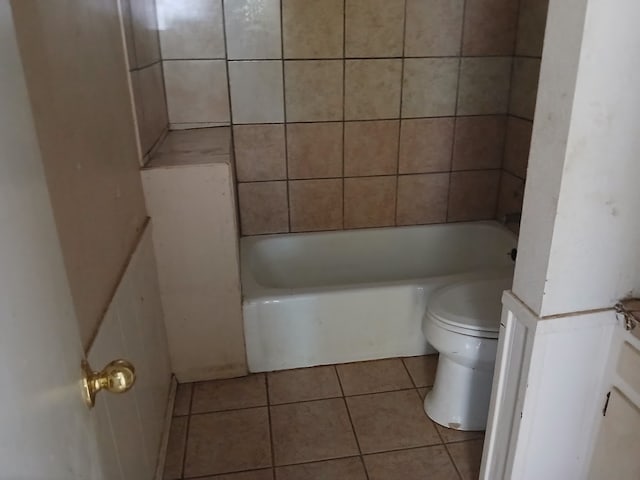 bathroom featuring a tub to relax in, toilet, and tile patterned flooring