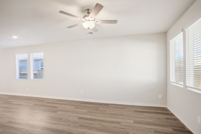 spare room with light hardwood / wood-style floors, a wealth of natural light, and ceiling fan