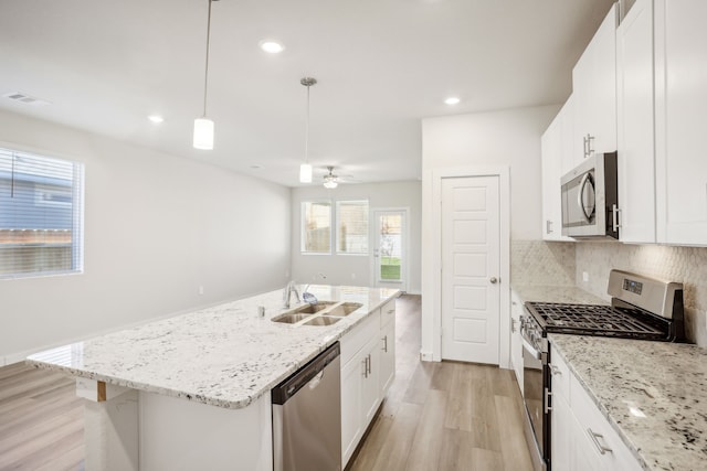 kitchen with sink, white cabinets, a center island with sink, and stainless steel appliances