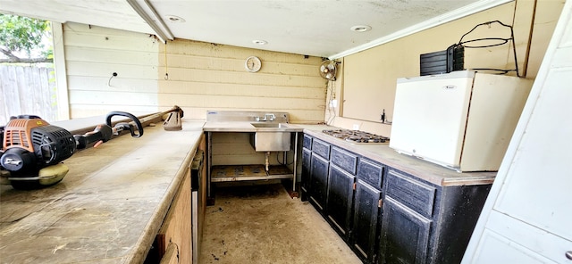 kitchen featuring ornamental molding, stainless steel gas cooktop, and wooden walls