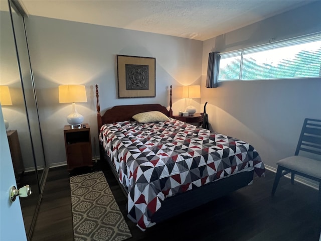 bedroom with a closet, dark hardwood / wood-style floors, and a textured ceiling