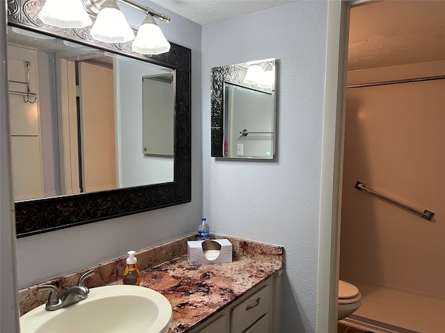 bathroom featuring a textured ceiling, vanity, and toilet