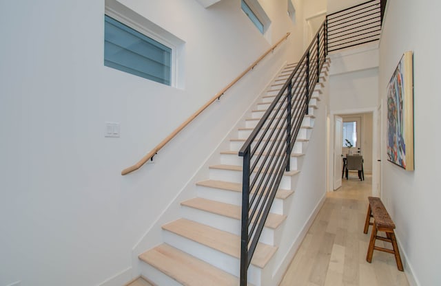 staircase with a towering ceiling and hardwood / wood-style flooring