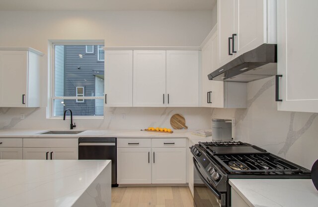 kitchen featuring light stone countertops, appliances with stainless steel finishes, sink, white cabinetry, and light wood-type flooring